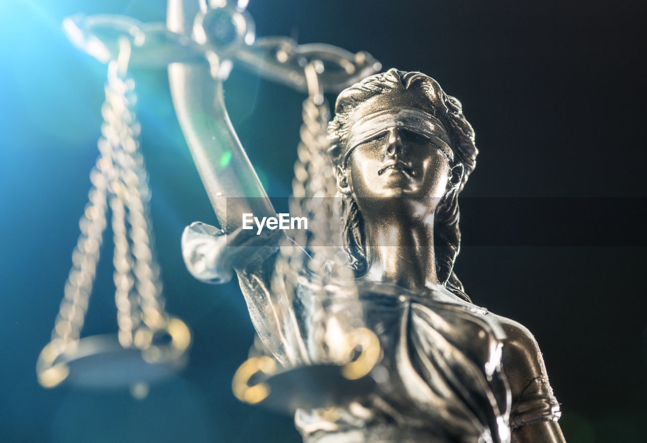 Close-up of lady justice statue against black background