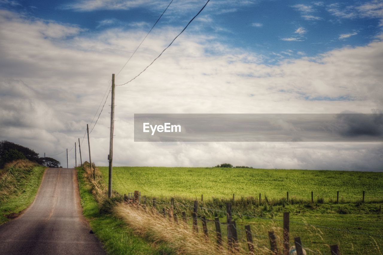 View of field against cloudy sky