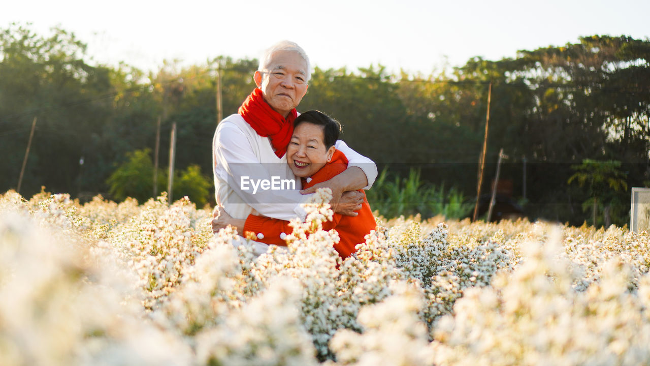 Asian senior elderly couple celebrating christmas holiday season white flower and red sweater 