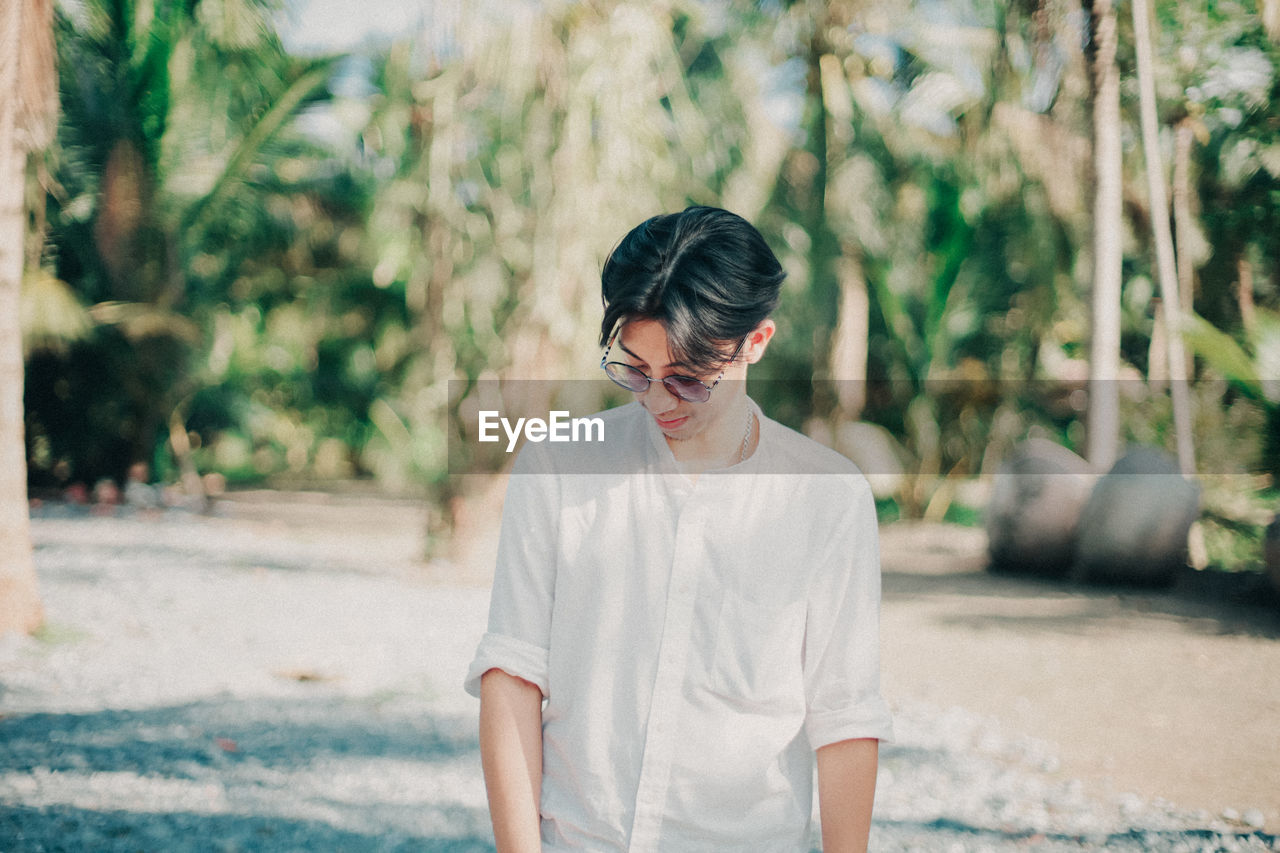 Young man looking away while standing outdoors