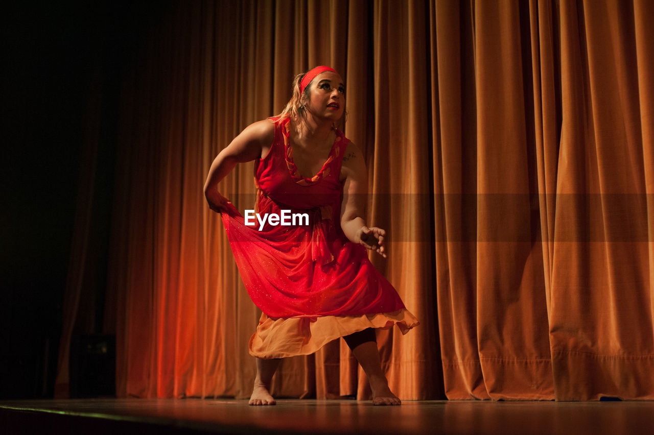 Full length of woman standing against curtain