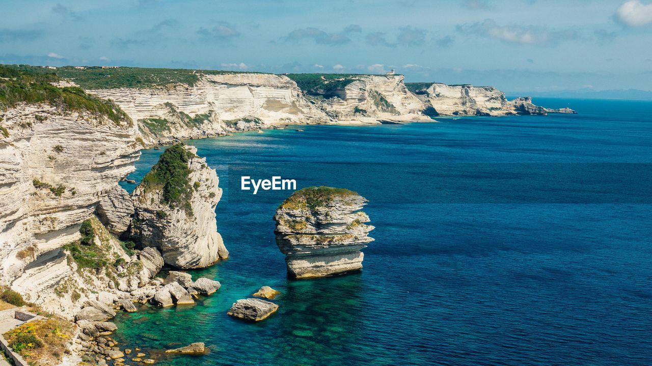 High angle view of rock formations by sea against sky