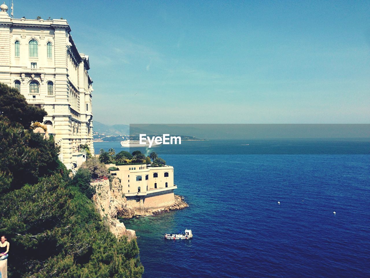 Buildings by sea against blue sky