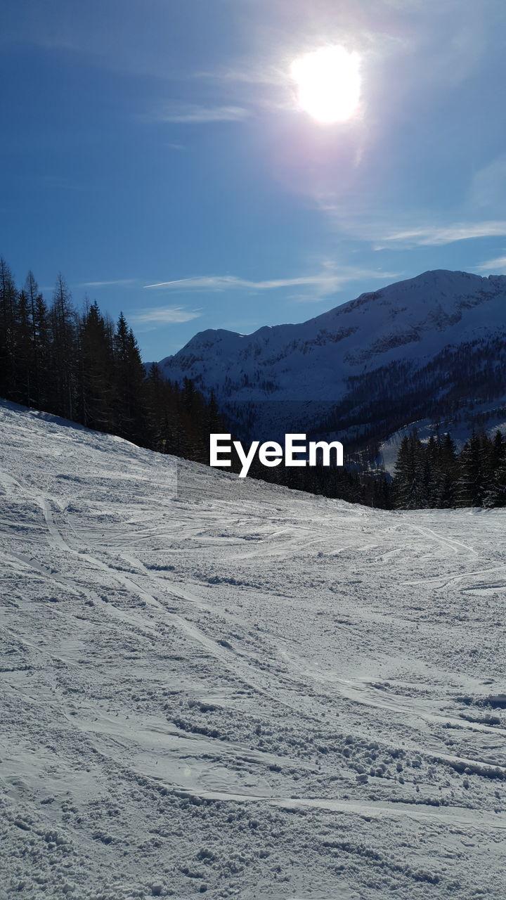Scenic view of snowcapped mountains with ski slopes against sky