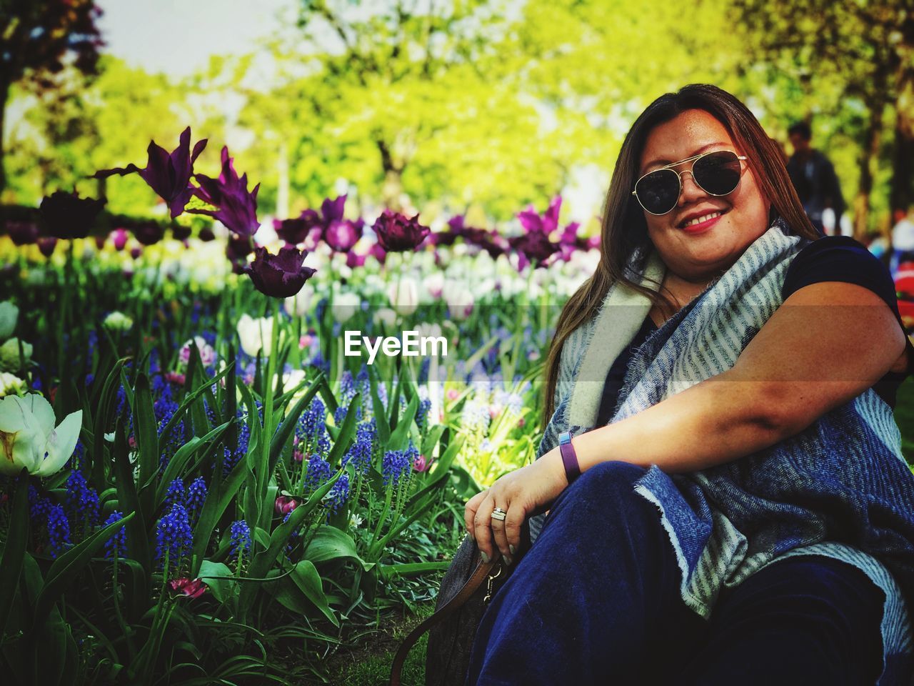 Portrait of smiling woman in sunglasses sitting on field