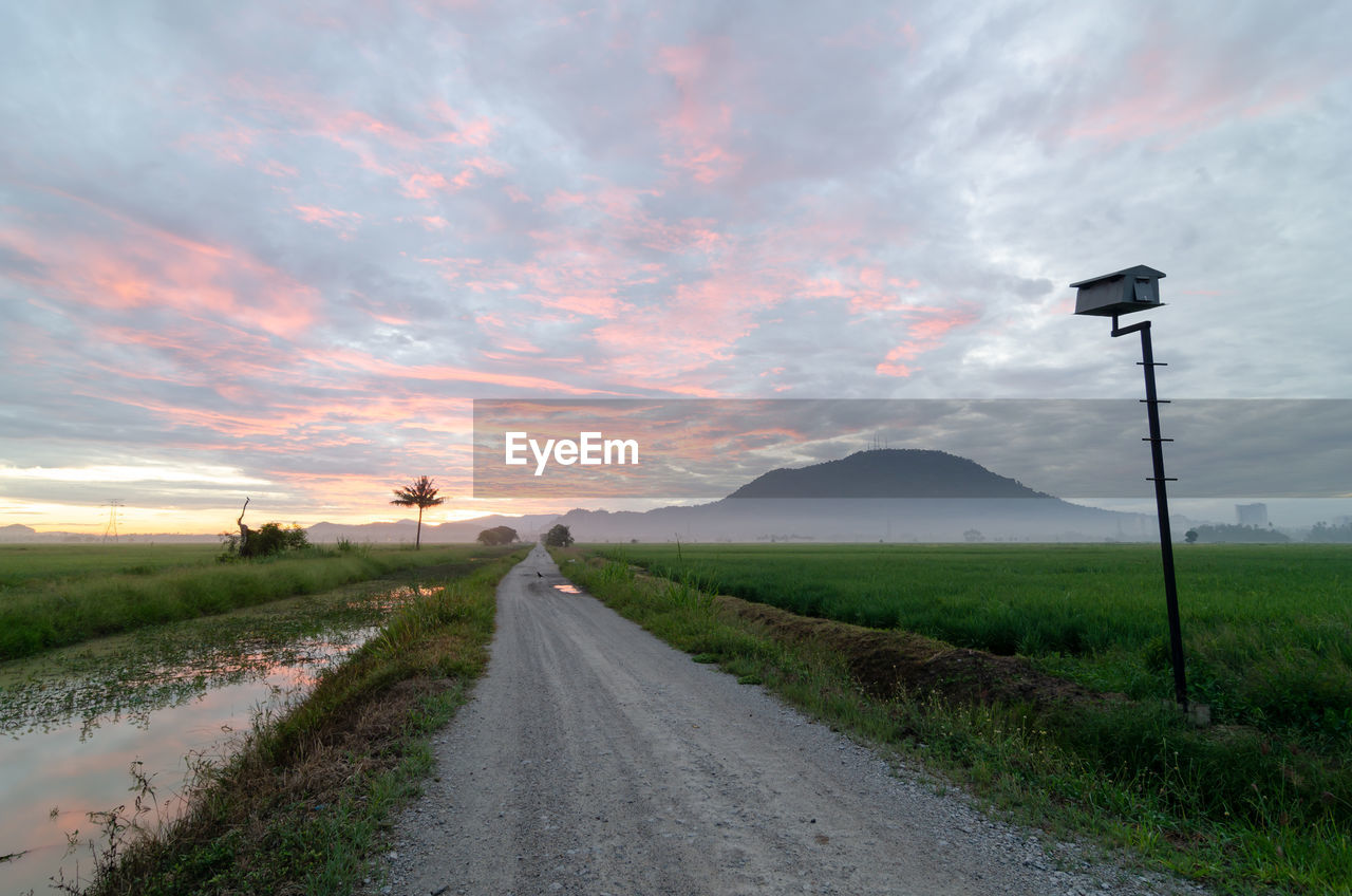 sky, cloud, landscape, road, environment, horizon, nature, rural area, hill, scenics - nature, beauty in nature, transportation, morning, grass, the way forward, land, plant, rural scene, no people, street, tranquility, field, prairie, infrastructure, highway, water, non-urban scene, tranquil scene, dramatic sky, outdoors, diminishing perspective, vanishing point, country road, coast, dirt road, travel, dawn, cloudscape, travel destinations, agriculture, plain