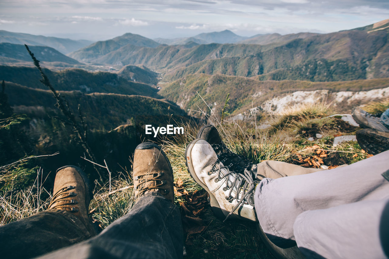 Low section of friends relaxing on mountain