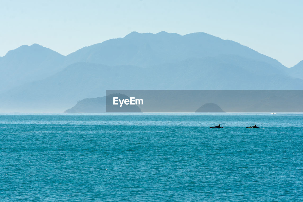 Scenic view of sea and mountains against clear sky