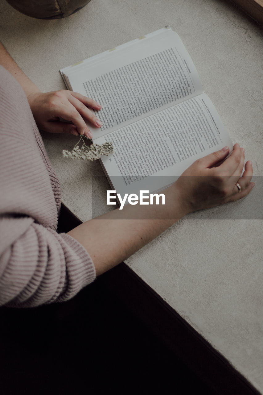 Midsection of woman reading book on table