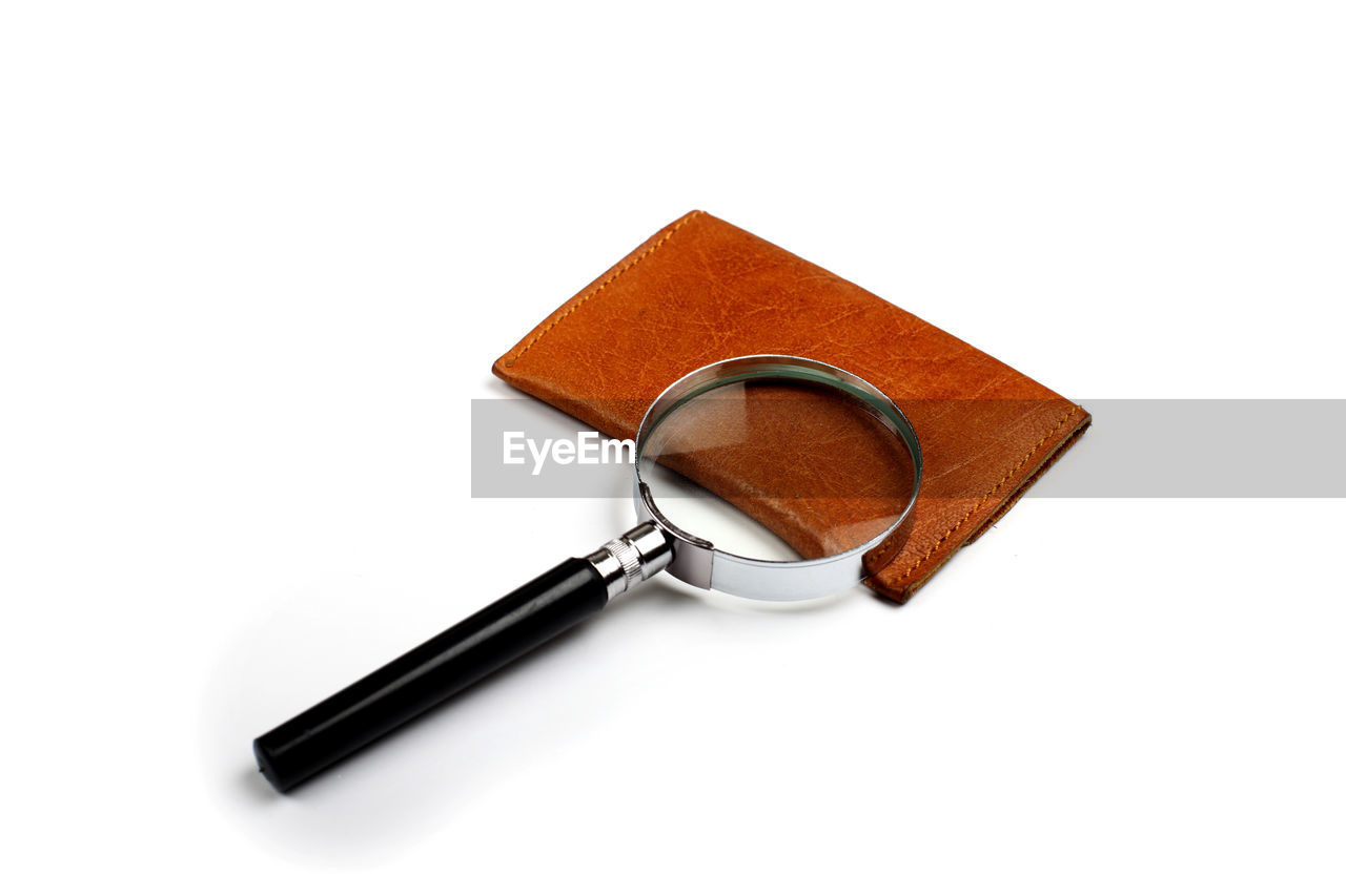 High angle view of magnifying glass with leather over white background