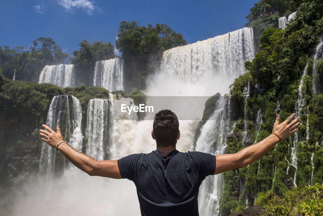 Young man posing in front of the iguacu waterfalls in argentina