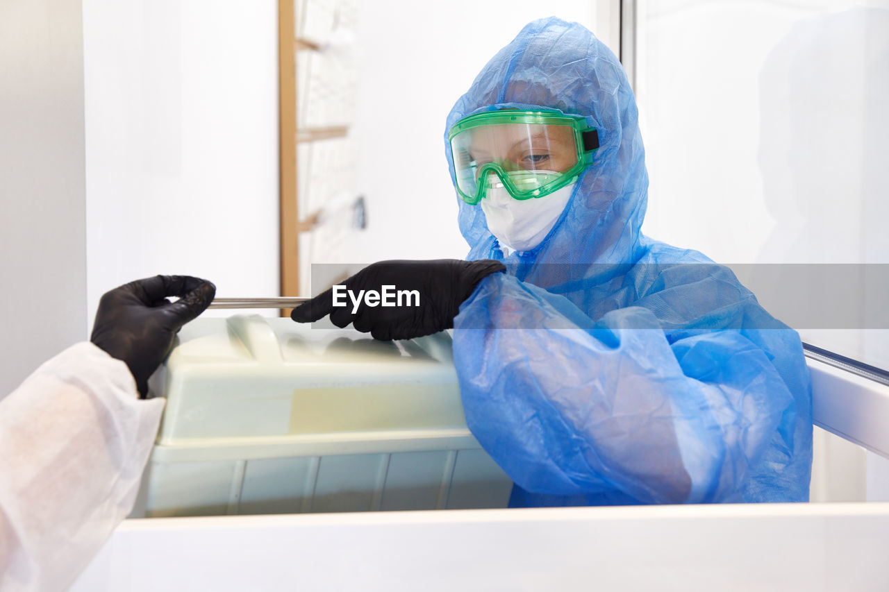 Scientist holding container while wearing protective suit