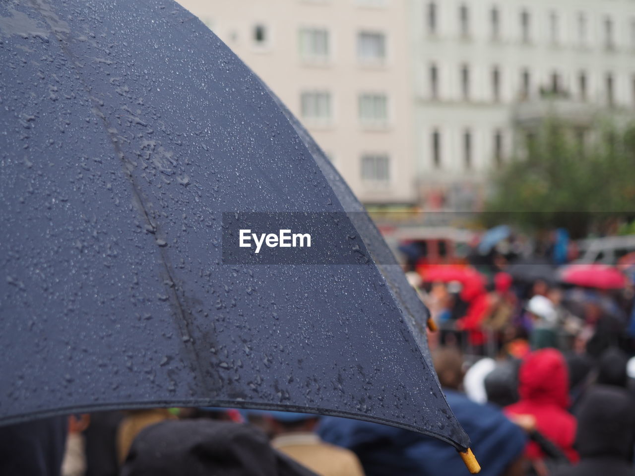 Close-up of wet umbrella with people in background