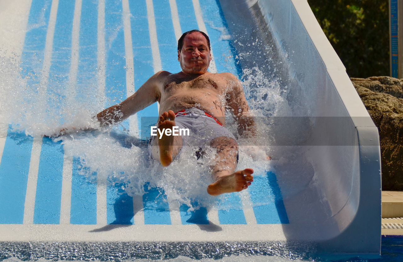 Portrait of man on water slide at amusement park