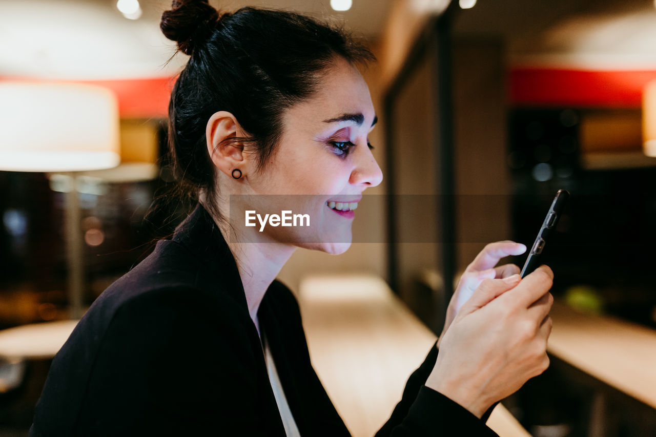 Smiling businesswoman using mobile phone at desk