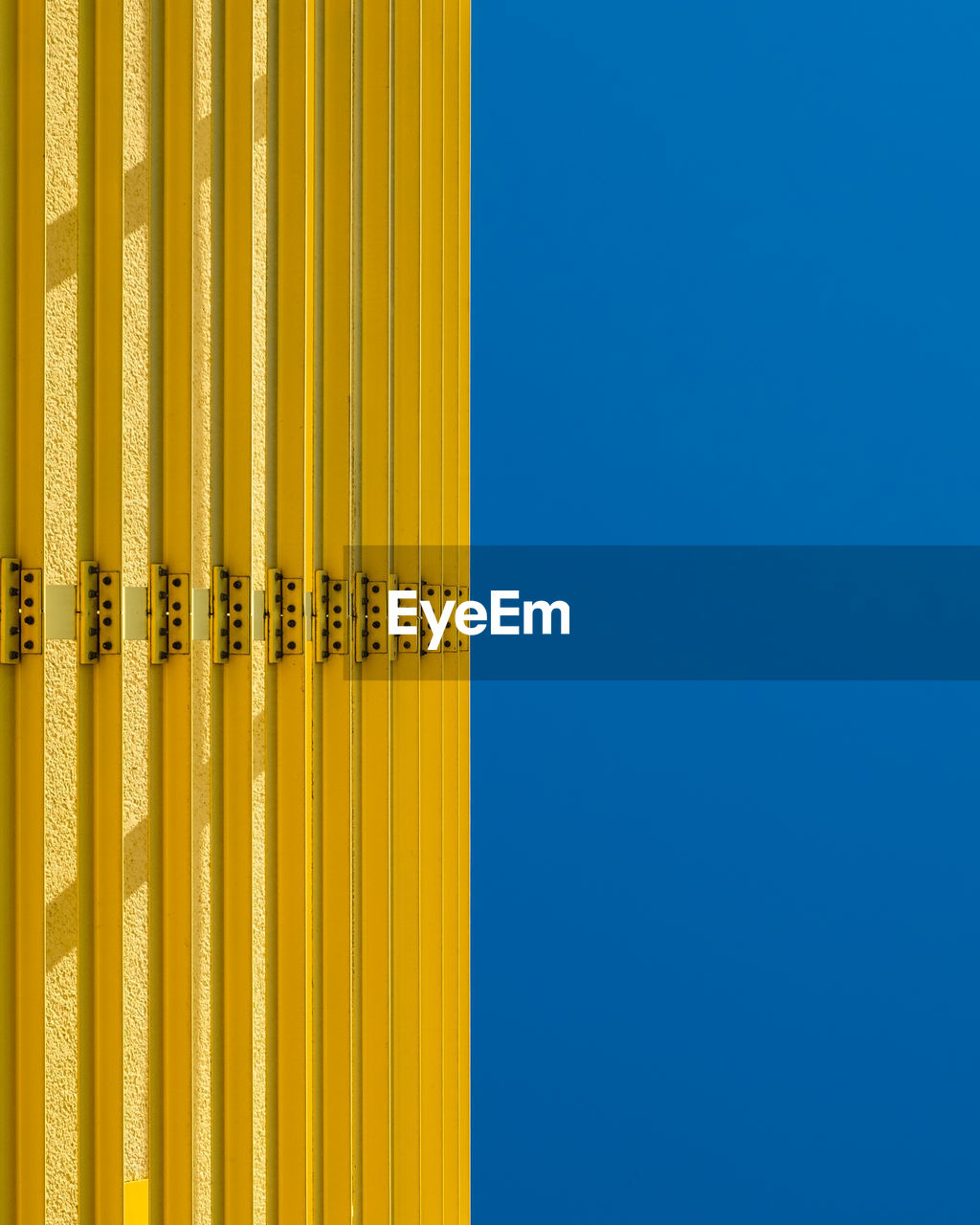 Close-up of yellow metal against blue sky