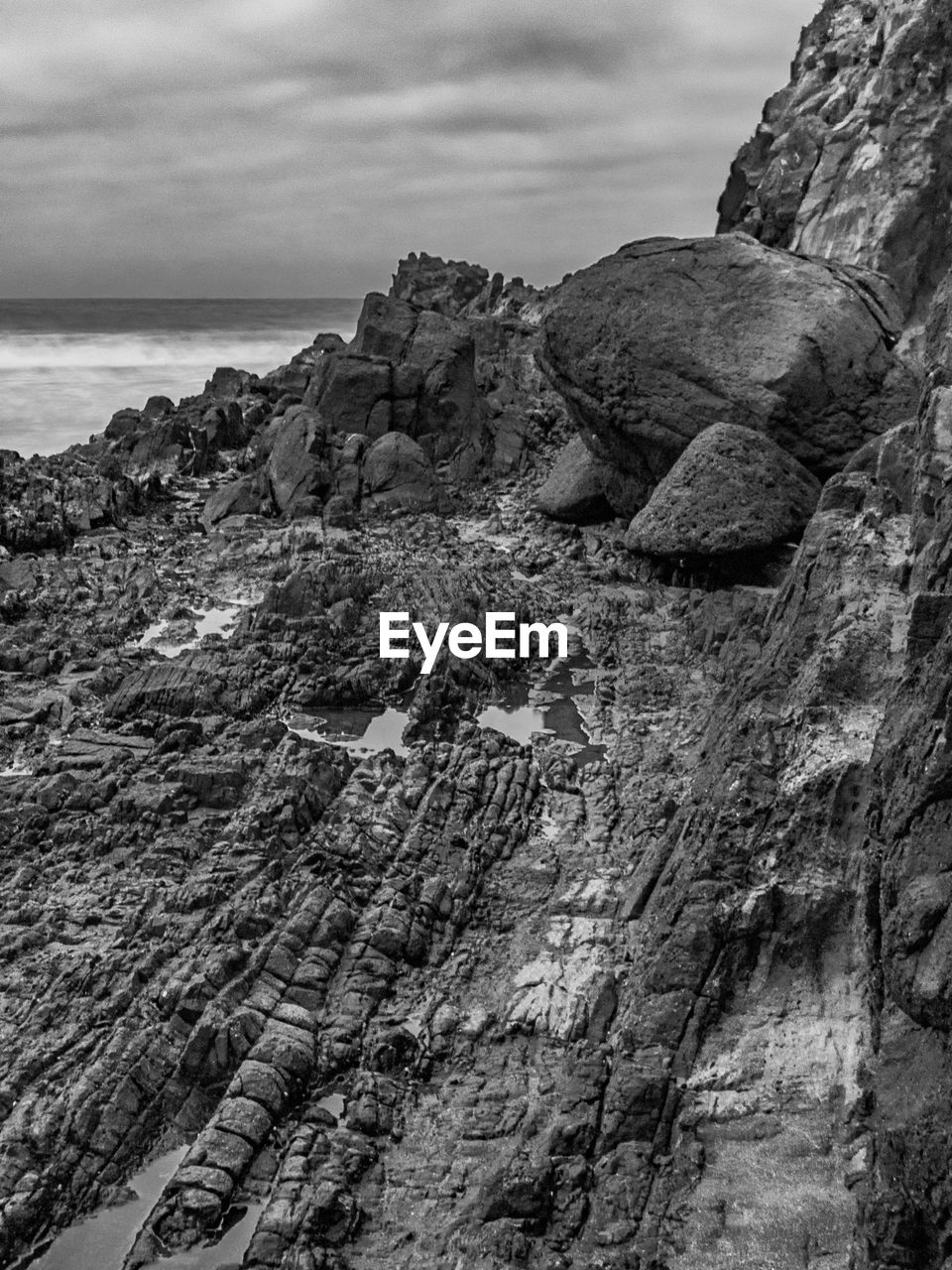 rock, black and white, coast, sea, land, sky, monochrome photography, cliff, nature, monochrome, scenics - nature, beauty in nature, rock formation, cloud, beach, water, terrain, mountain, no people, geology, environment, landscape, tranquility, outdoors, non-urban scene, day, travel destinations, ocean, tranquil scene, shore, travel, black