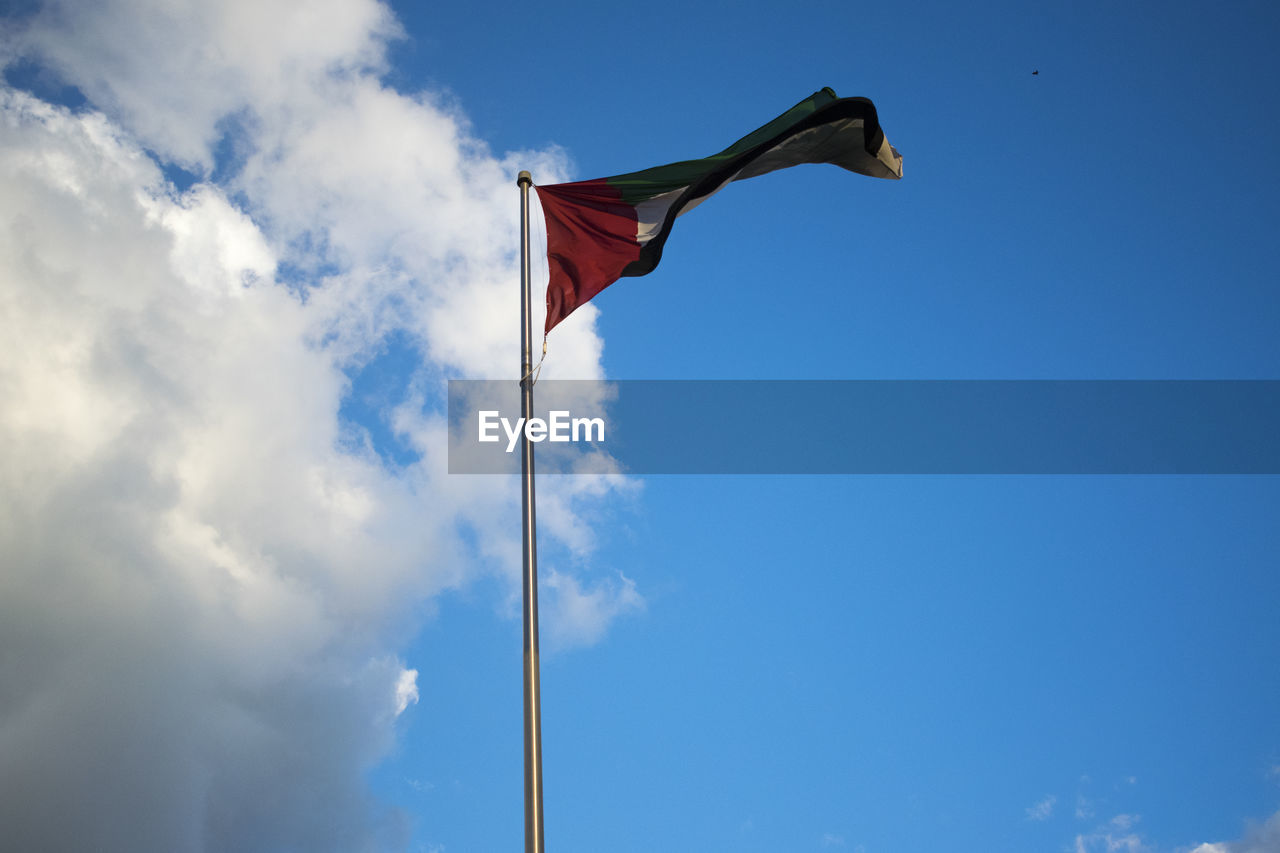 LOW ANGLE VIEW OF FLAGS AGAINST CLOUDY SKY