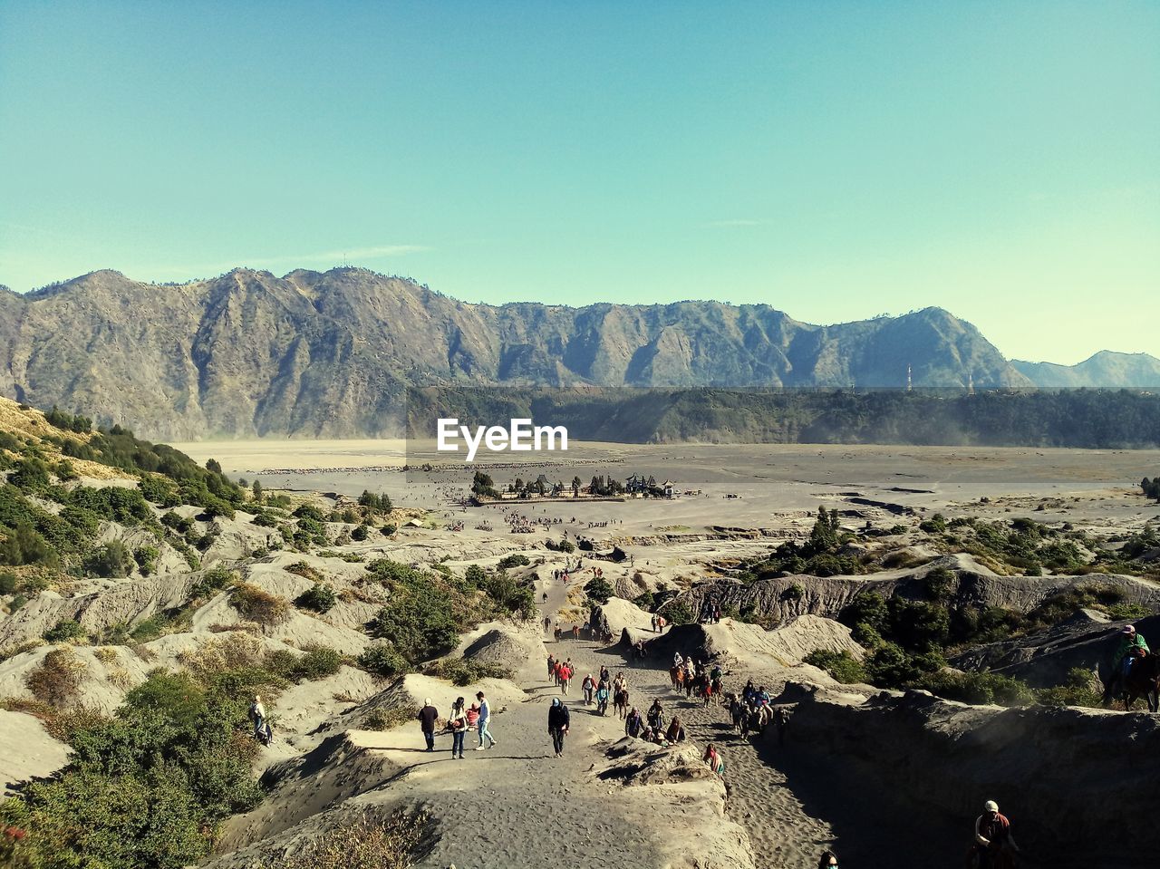 People walking on mountain road against clear sky