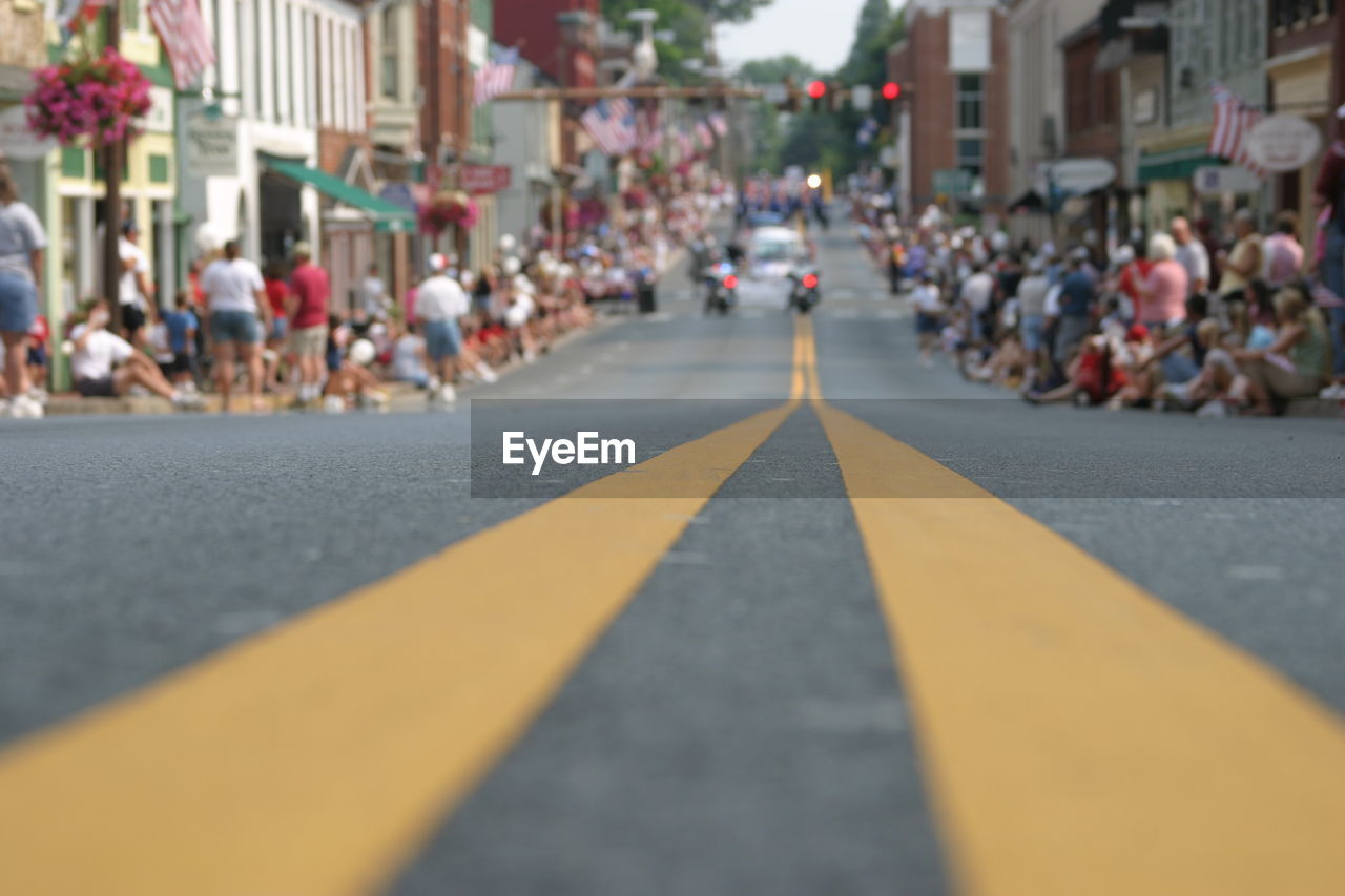 Surface level of road amidst people sitting against buildings