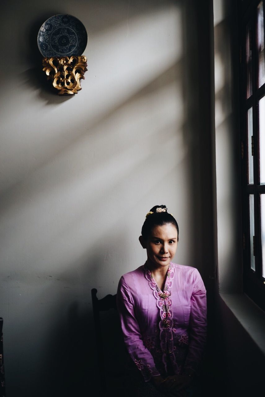 Portrait of young woman sitting on chair at home