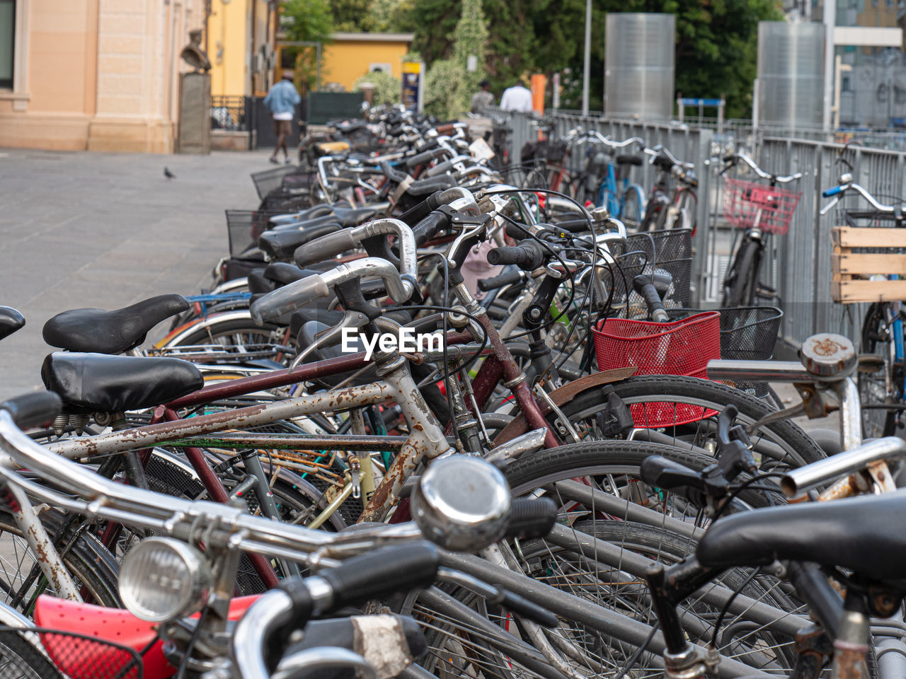 Many old bicycles padlocked to the rack near train station.