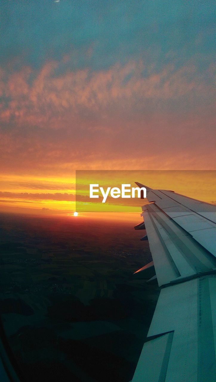 Airplane wing against sky during sunset