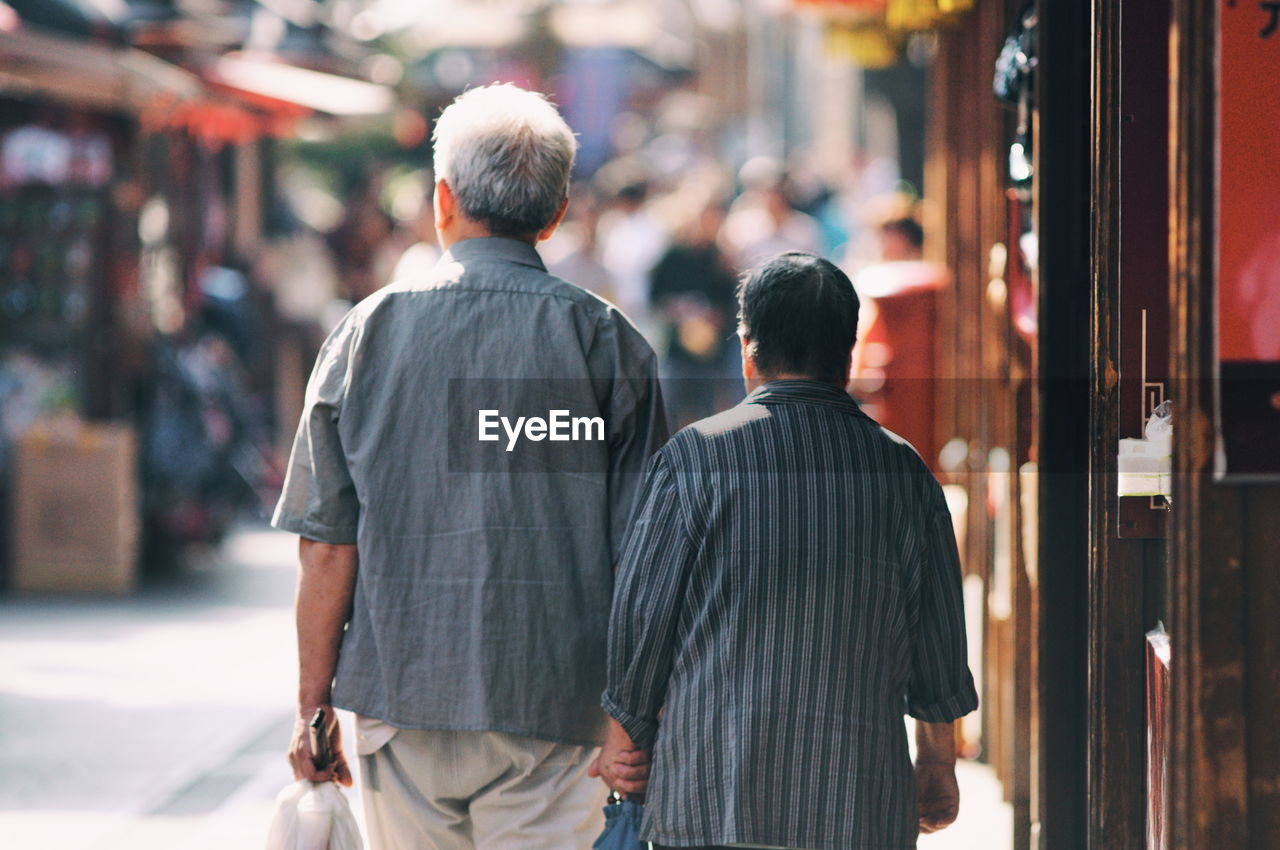 REAR VIEW OF MEN WALKING ON STREET