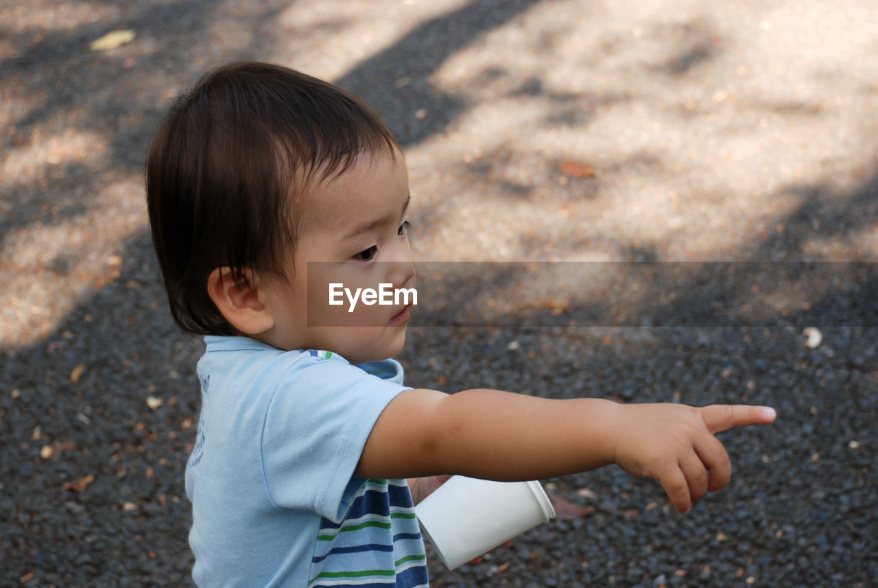 High angle view of boy pointing while standing on footpath