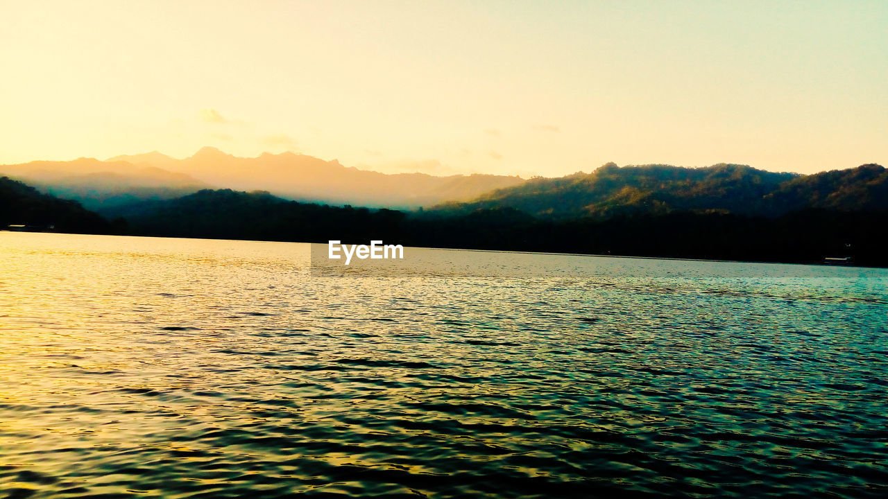 SCENIC VIEW OF LAKE BY SILHOUETTE MOUNTAINS AGAINST CLEAR SKY