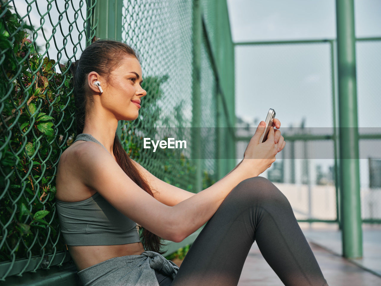 side view of young woman sitting on railing