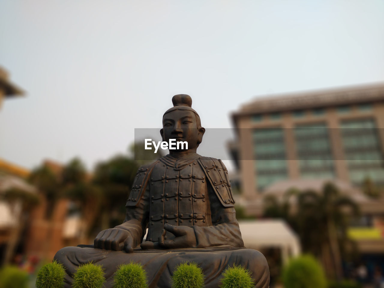 Low angle view of buddha statue against clear sky in park at dusk