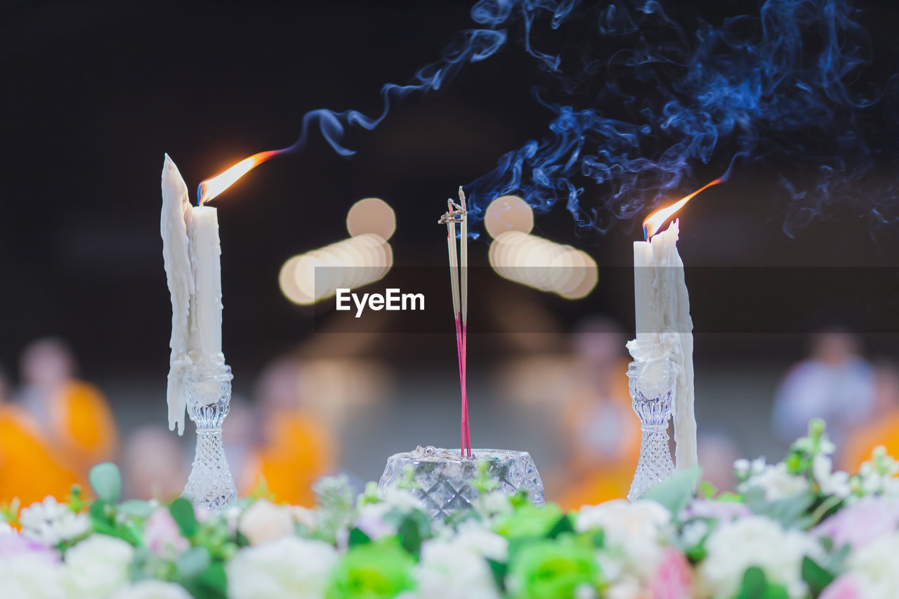 Close-up of lit candles and incense in temple