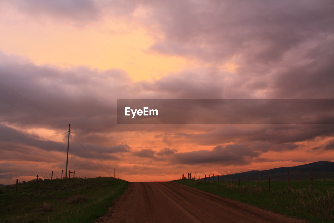 Road amidst land against sky during sunset