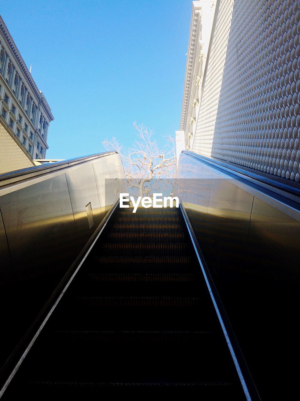 Low angle view of escalator and city buildings