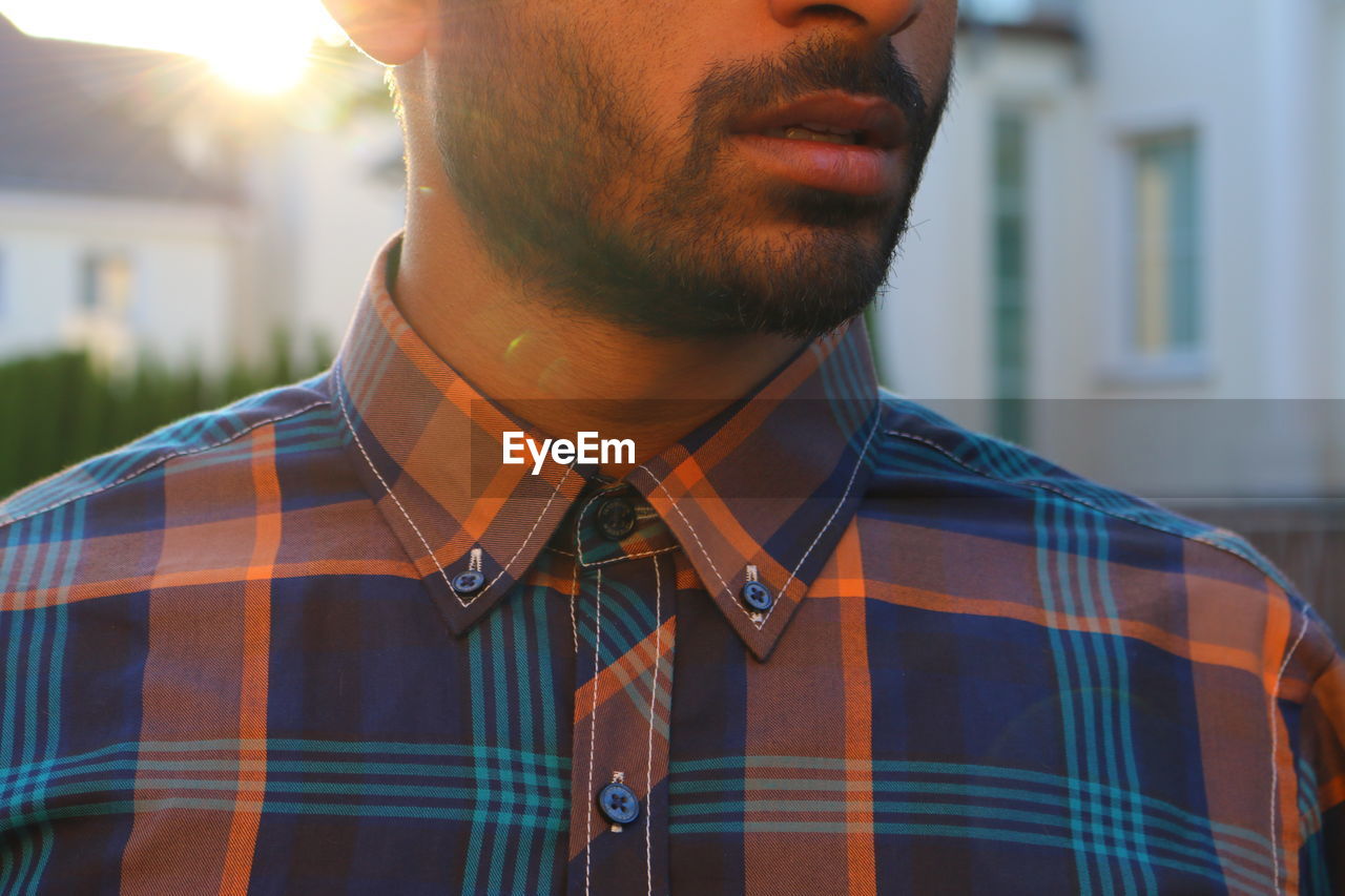 Midsection of man in button down shirt standing against building