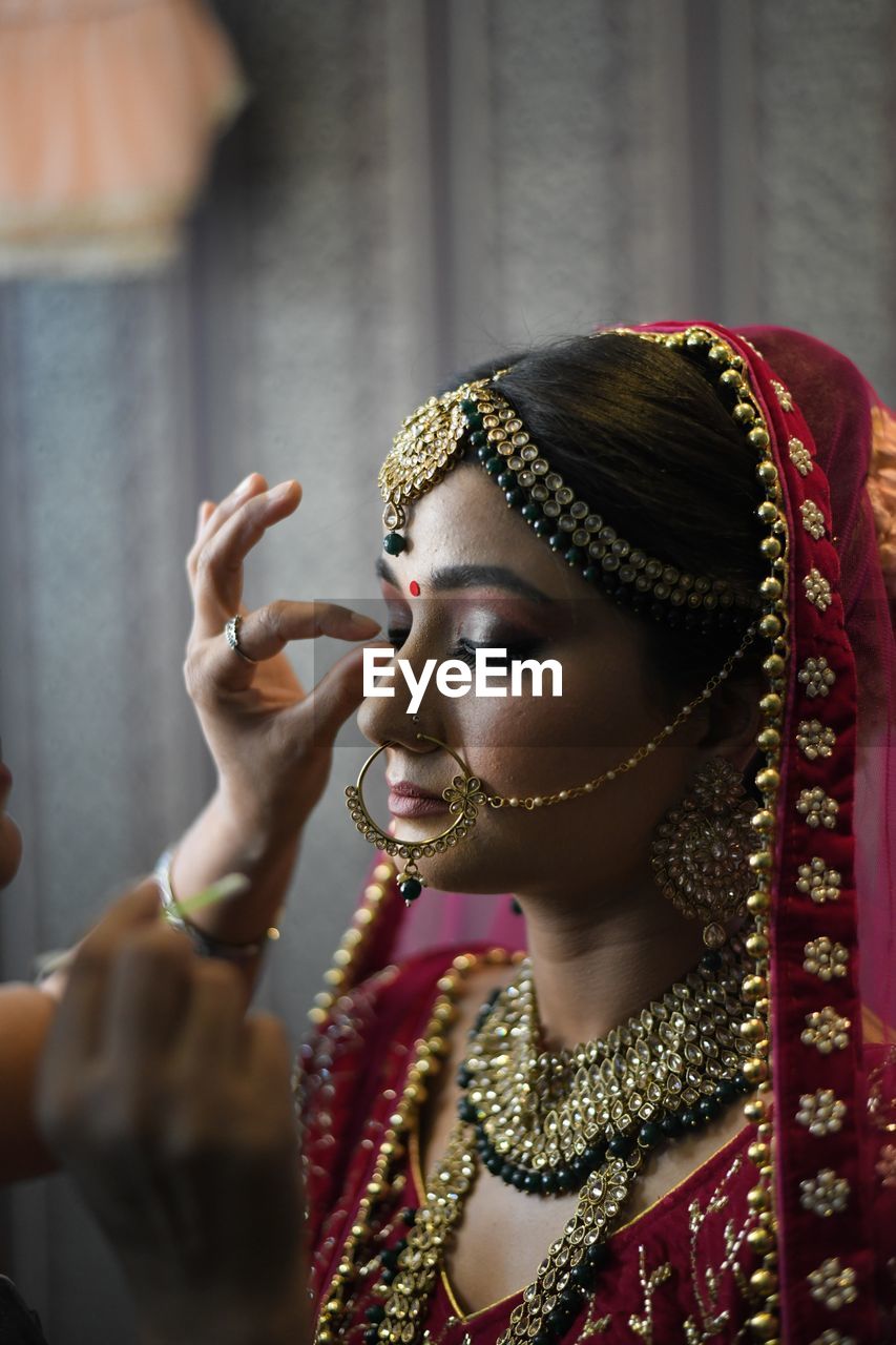 Beautician applying make-up to bride