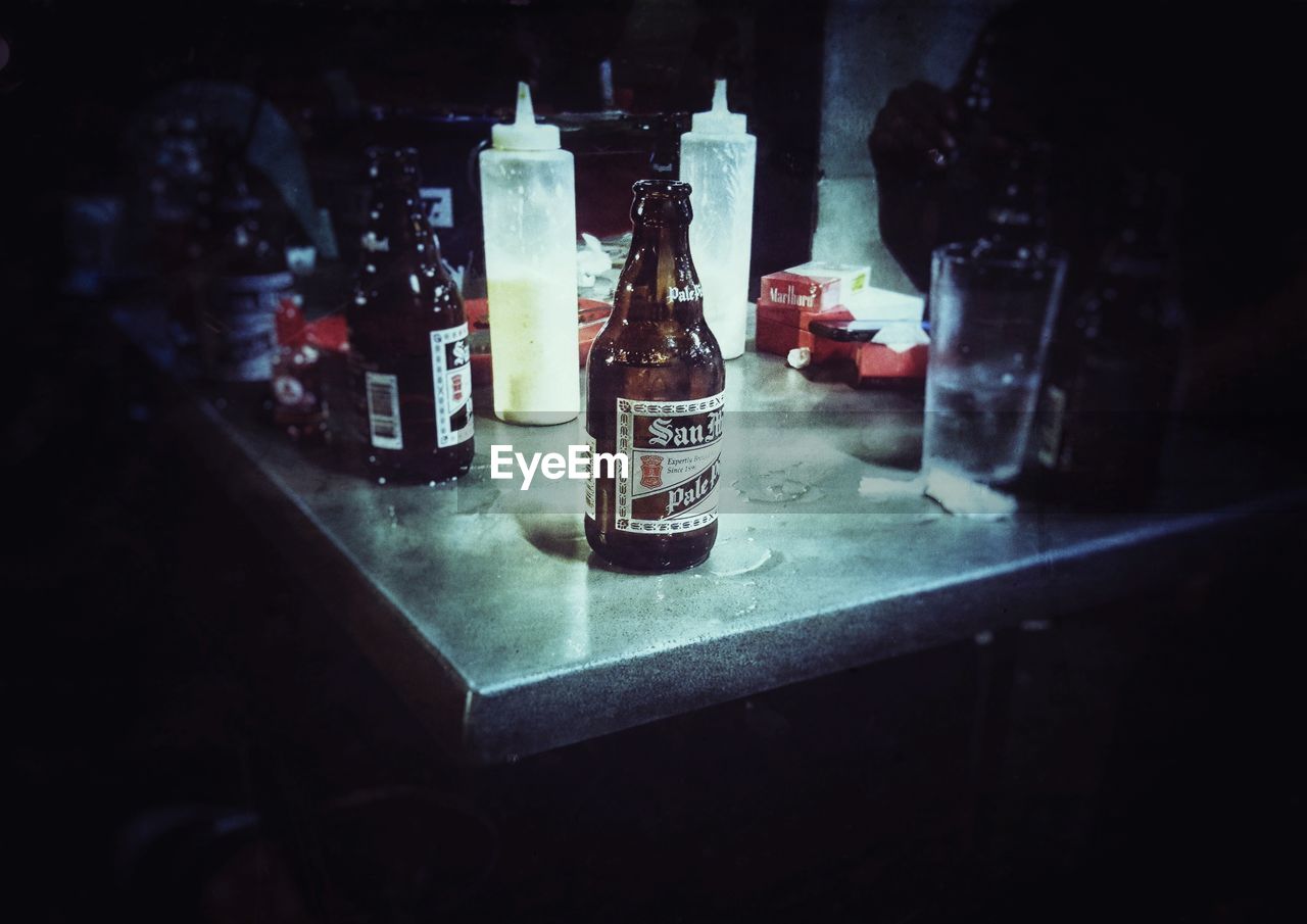 CLOSE-UP OF BOTTLES IN JAR ON TABLE