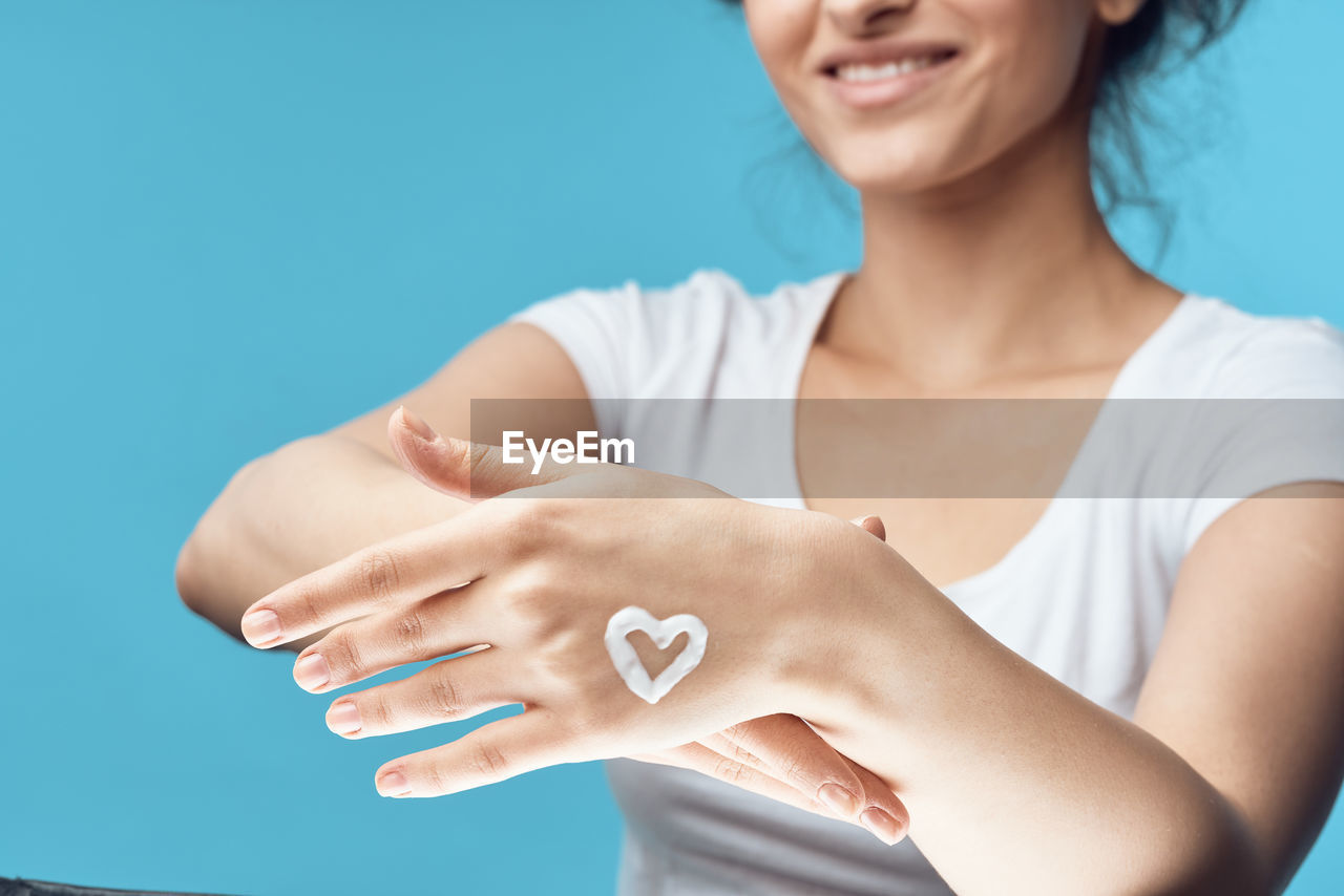 Midsection of smiling woman against blue background