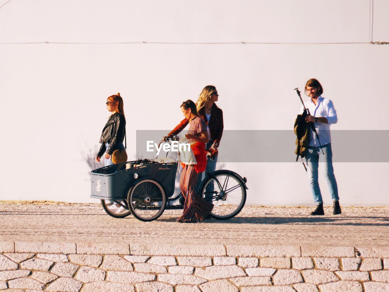 PEOPLE WITH BICYCLE STANDING ON WALL