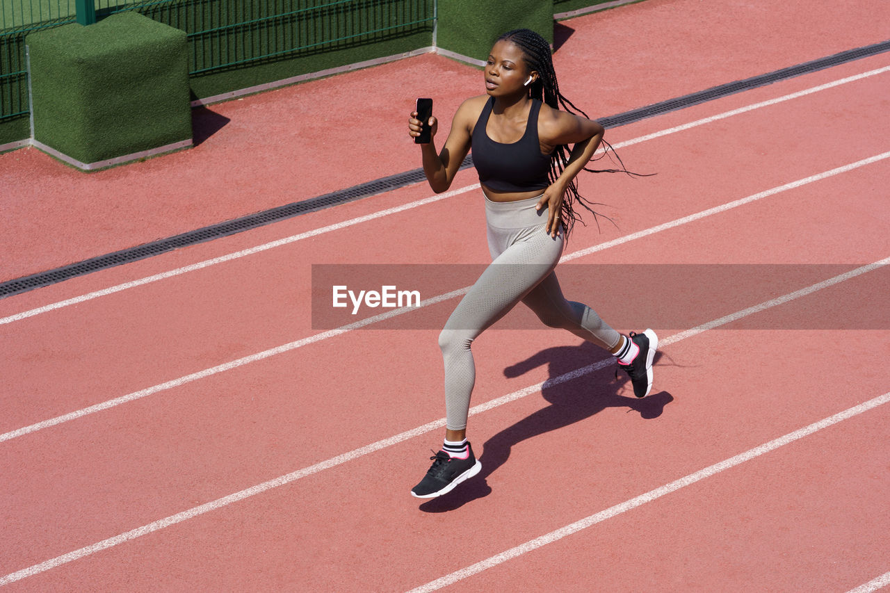 African woman athlete running on racetrack. sportive black female training jog on stadium sprinting