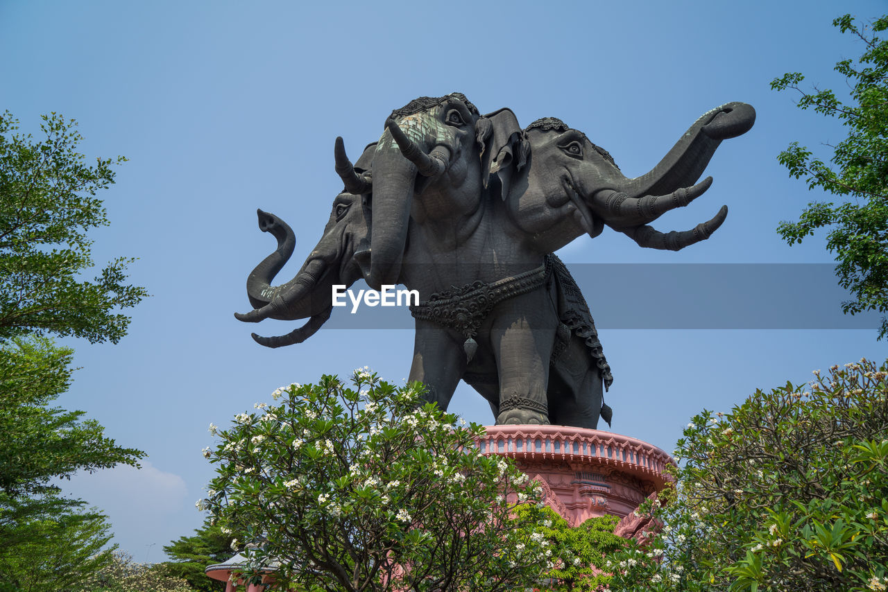 Low angle view of animal statue against clear blue sky