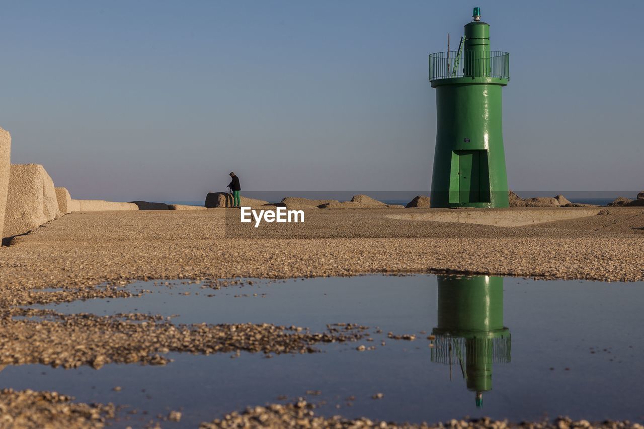 LIGHTHOUSE AT SHORE AGAINST SKY