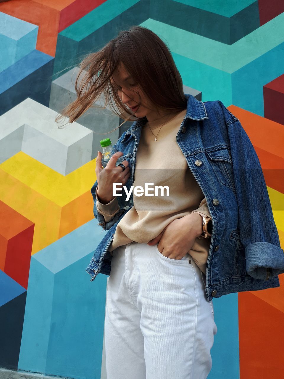 Young woman standing against wall