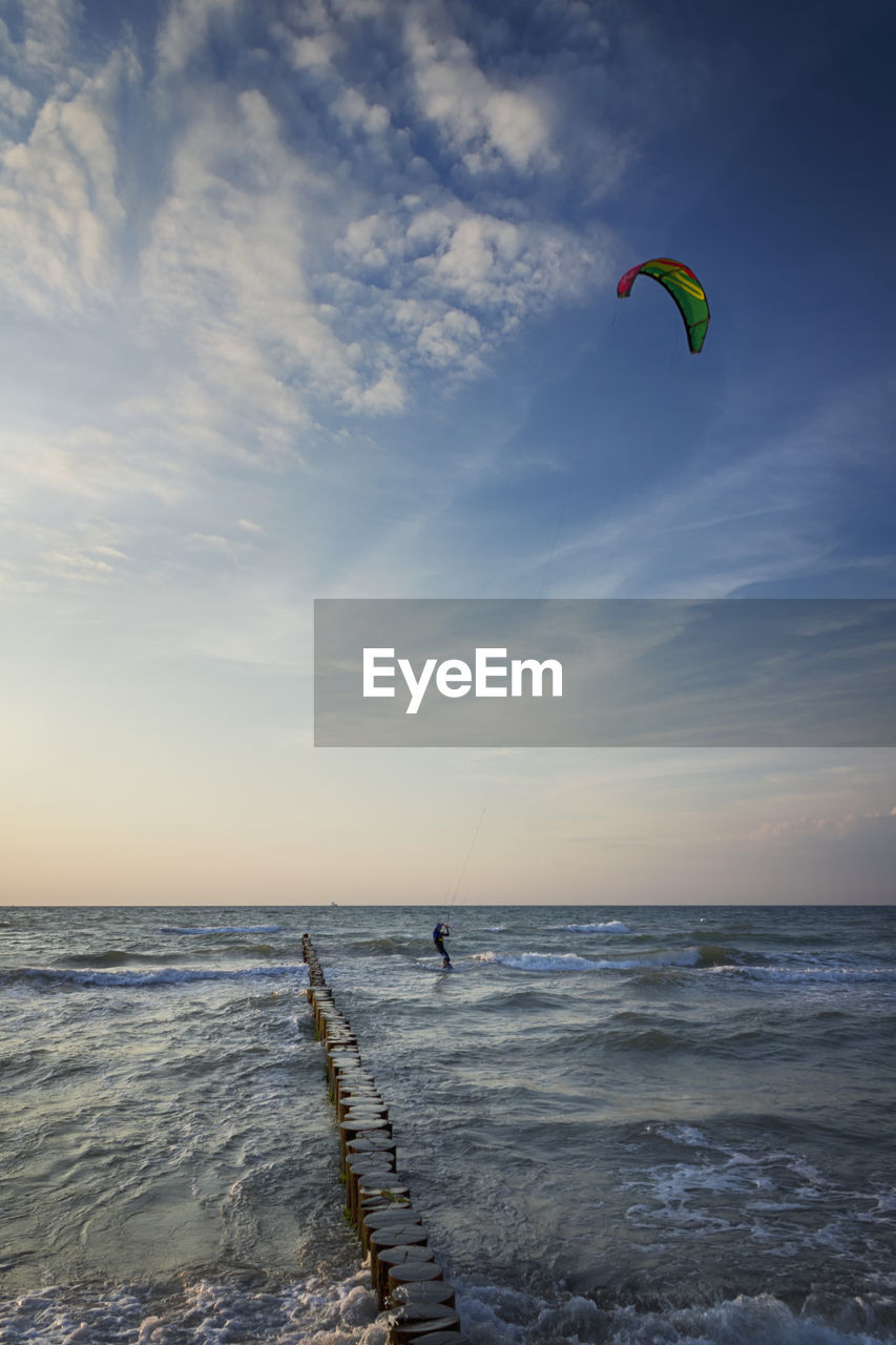 PEOPLE PARAGLIDING IN SEA AGAINST SKY