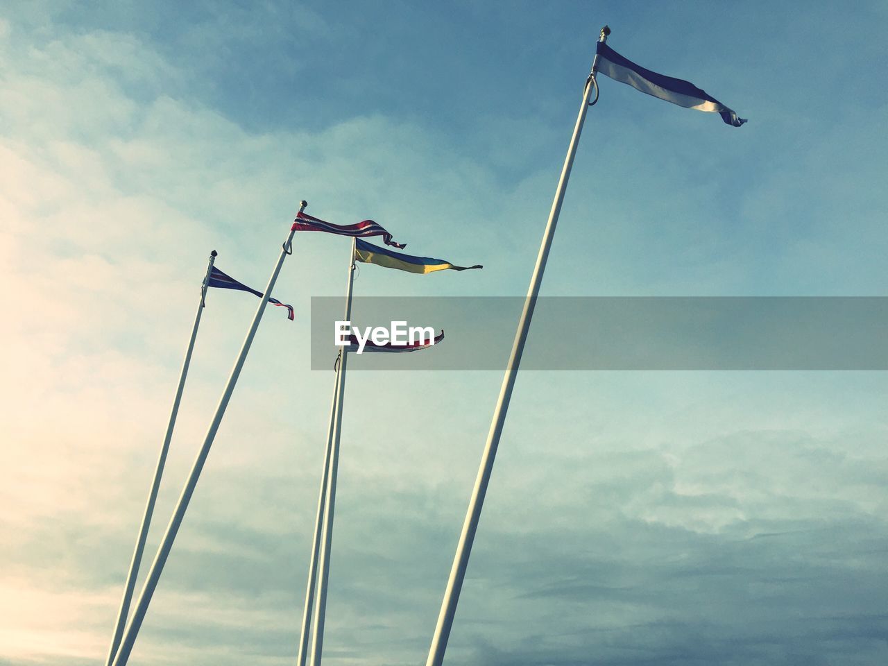 Low angle view of flags against cloudy sky