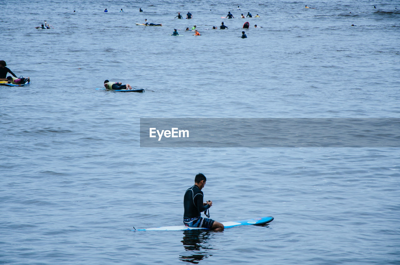 Man sitting on surfboard in sea