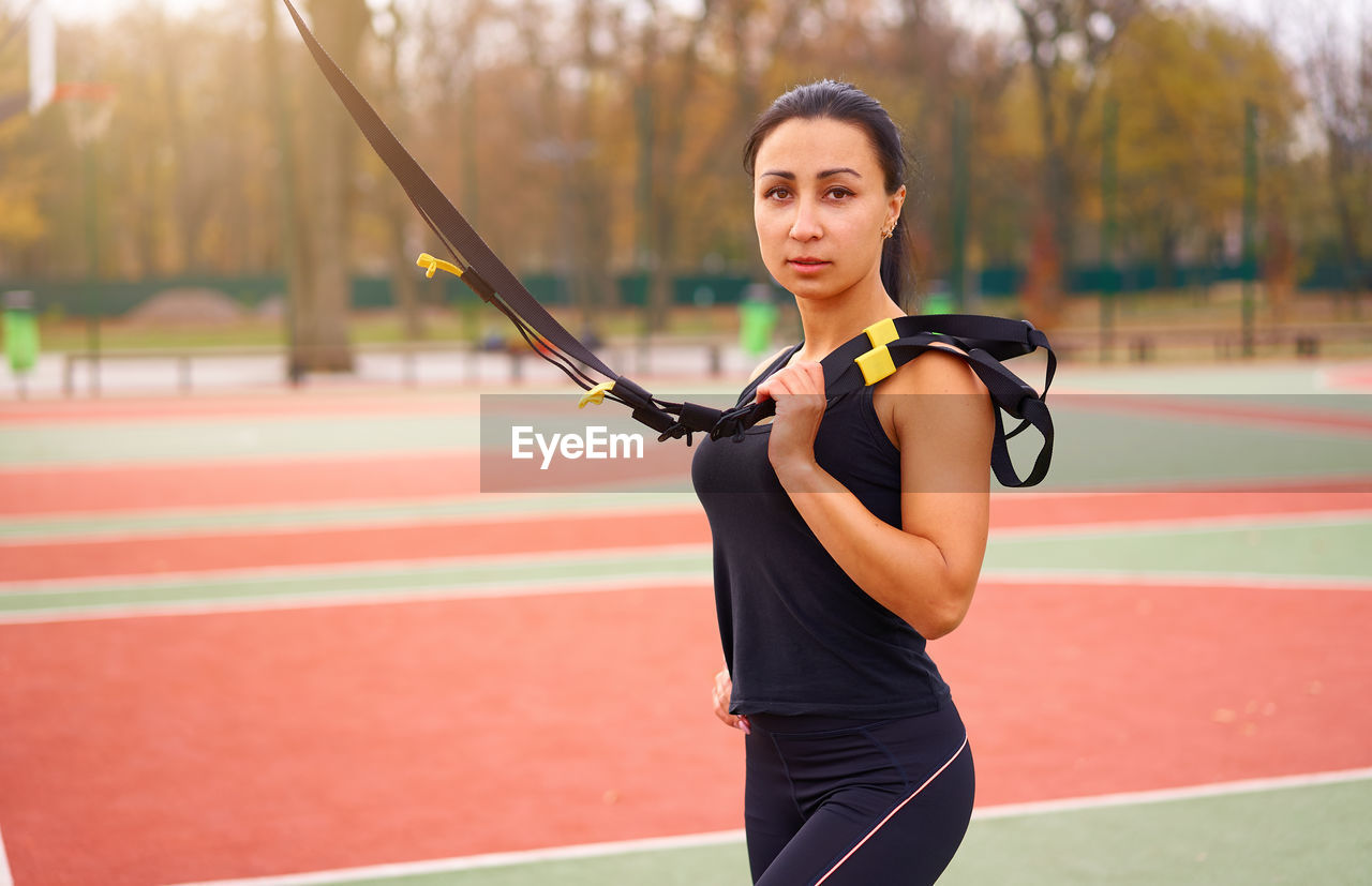 Portrait of smiling woman exercising with equipment at court