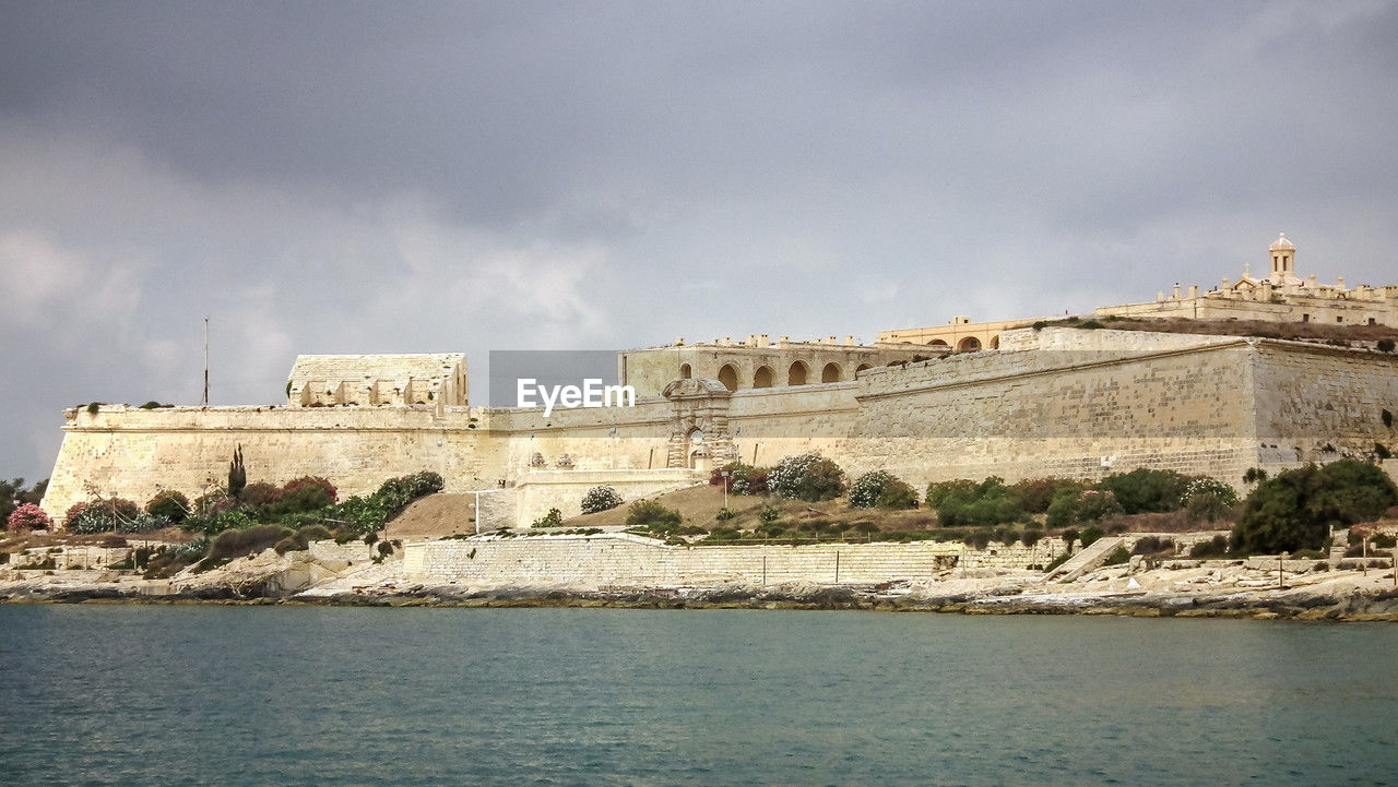 architecture, sea, water, built structure, history, sky, building exterior, travel destinations, the past, cloud, coast, nature, travel, building, fortification, fort, tourism, city, castle, landmark, outdoors, no people, land, wall, ancient, day, old, ancient history, medieval, fortified wall, ocean, environment, vacation, overcast