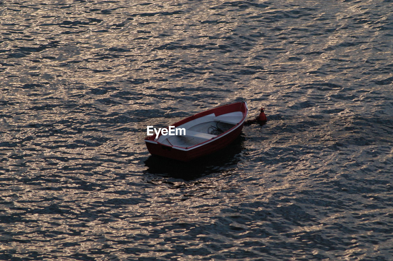 High angle view of empty boat moored on sea at sunset